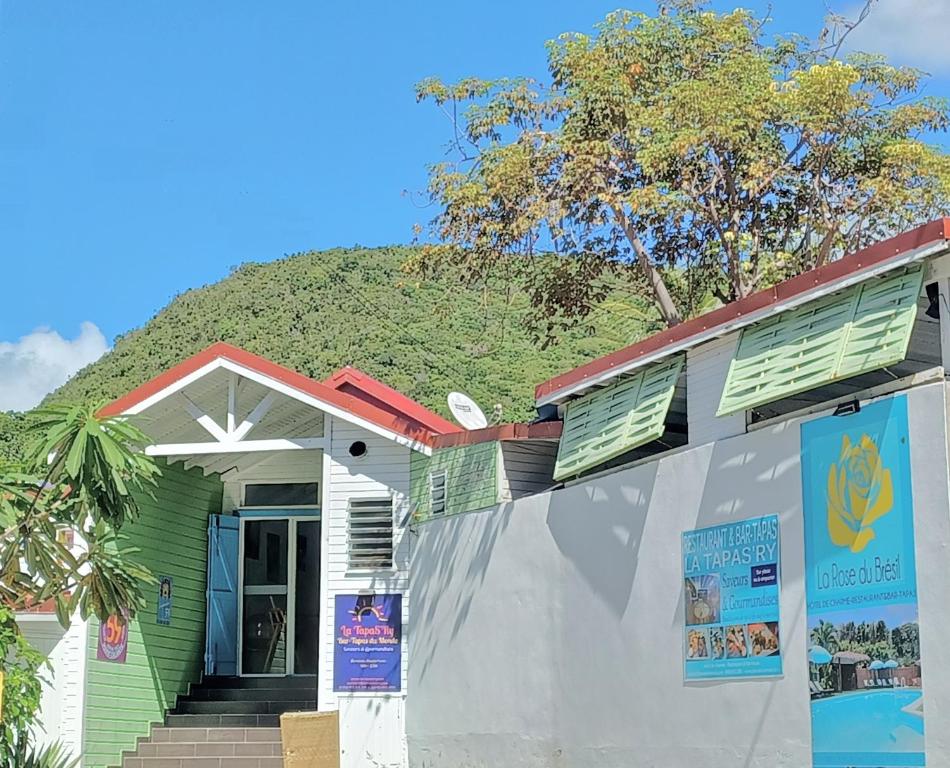 a house with a grassy hill behind it at La Rose du Bresil Marie-Galante in Capesterre