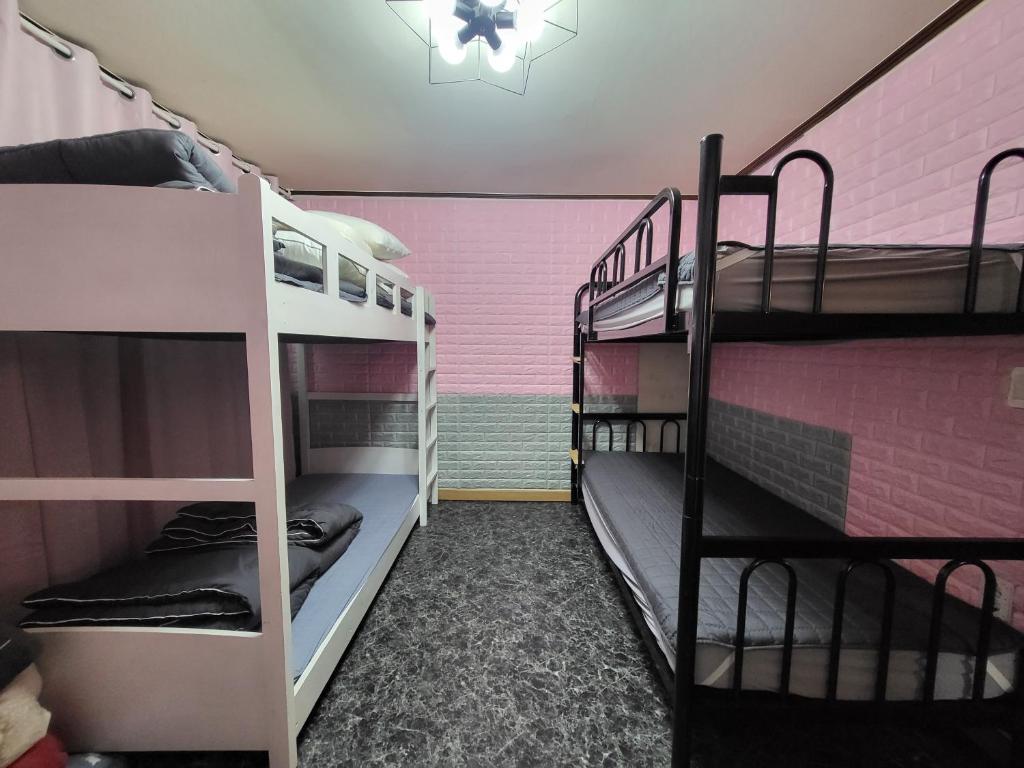 a room with two bunk beds and a pink wall at DB House in Seoul