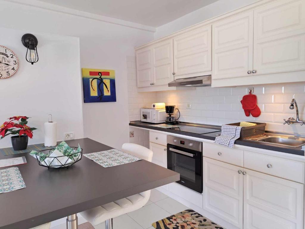 cocina con armarios blancos y encimera negra en Sunny Tenerife Apartment - ocean views, en Tacoronte