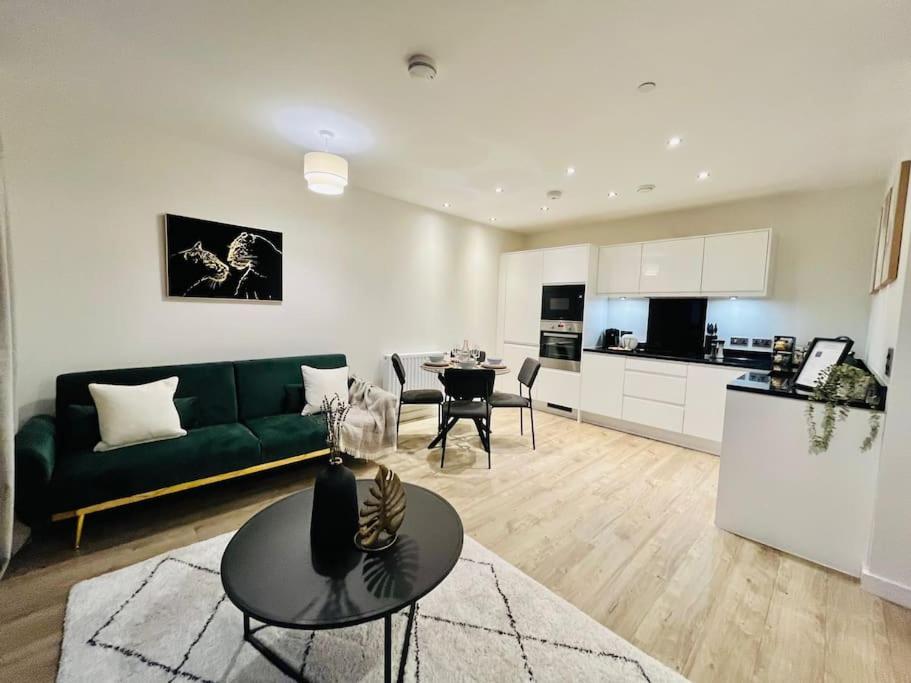 a living room with a green couch and a table at High-Spec Skyline Apartment in London - 2 BDR & Balcony in London