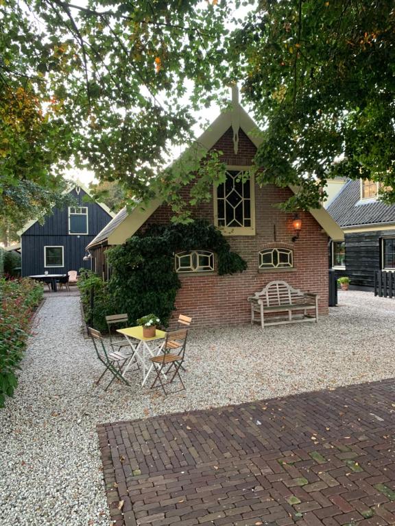 een stenen huis met een tafel en stoelen ervoor bij Op Stolk bed & breakfast in Stolwijk