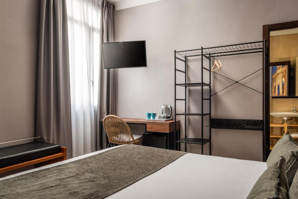 um quarto de hotel com uma cama e uma secretária em BYPILLOW The Citadel em Madrid