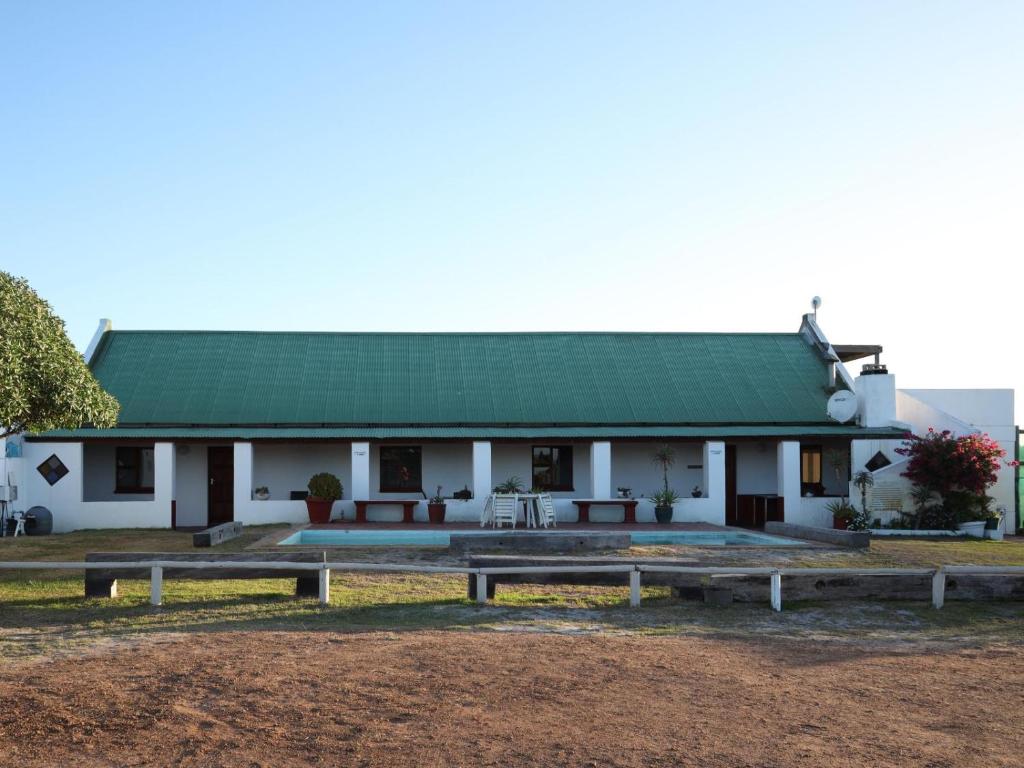 un edificio blanco con techo verde y bancos en Tula Guest Farm en Yzerfontein