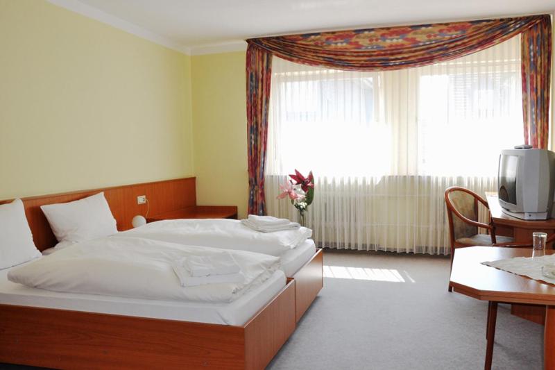 a bedroom with a bed and a desk and a tv at Hotel Hessischer Hof in Kirchhain