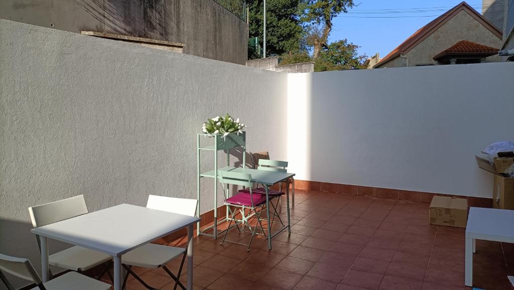 un patio con tavoli, sedie e parete bianca di Apartamento en Pontevedra con terraza y garaje a Poio