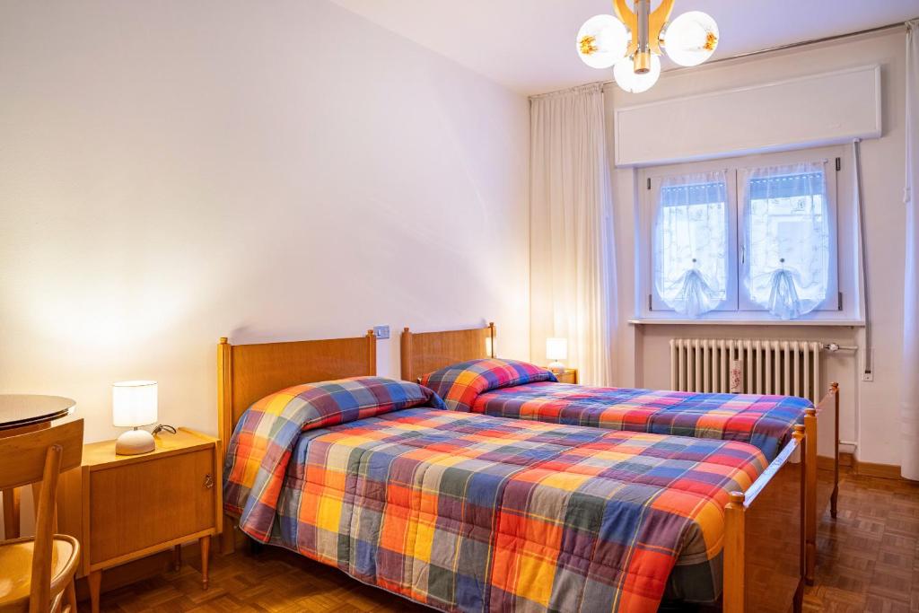 a bedroom with two beds and a table and a window at Appartamento Piazzi 2 in Caderzone