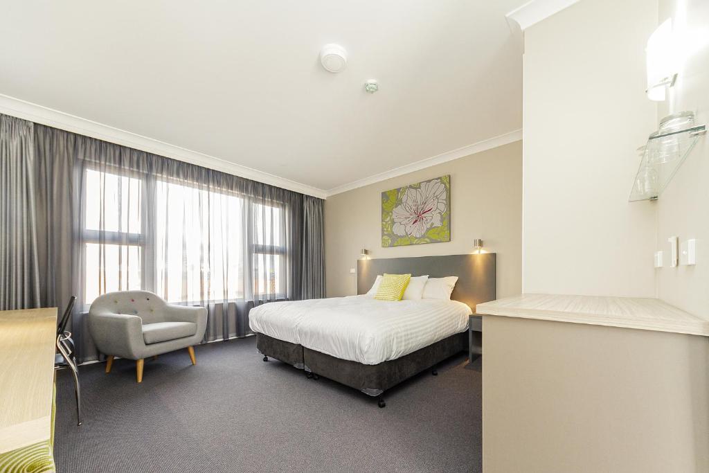 a hotel room with a bed and a chair at Cowra Services Club Motel in Cowra