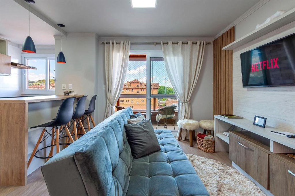 sala de estar con sofá azul y cocina en Campos de Canela 402 - Stay House Temporada, en Canela