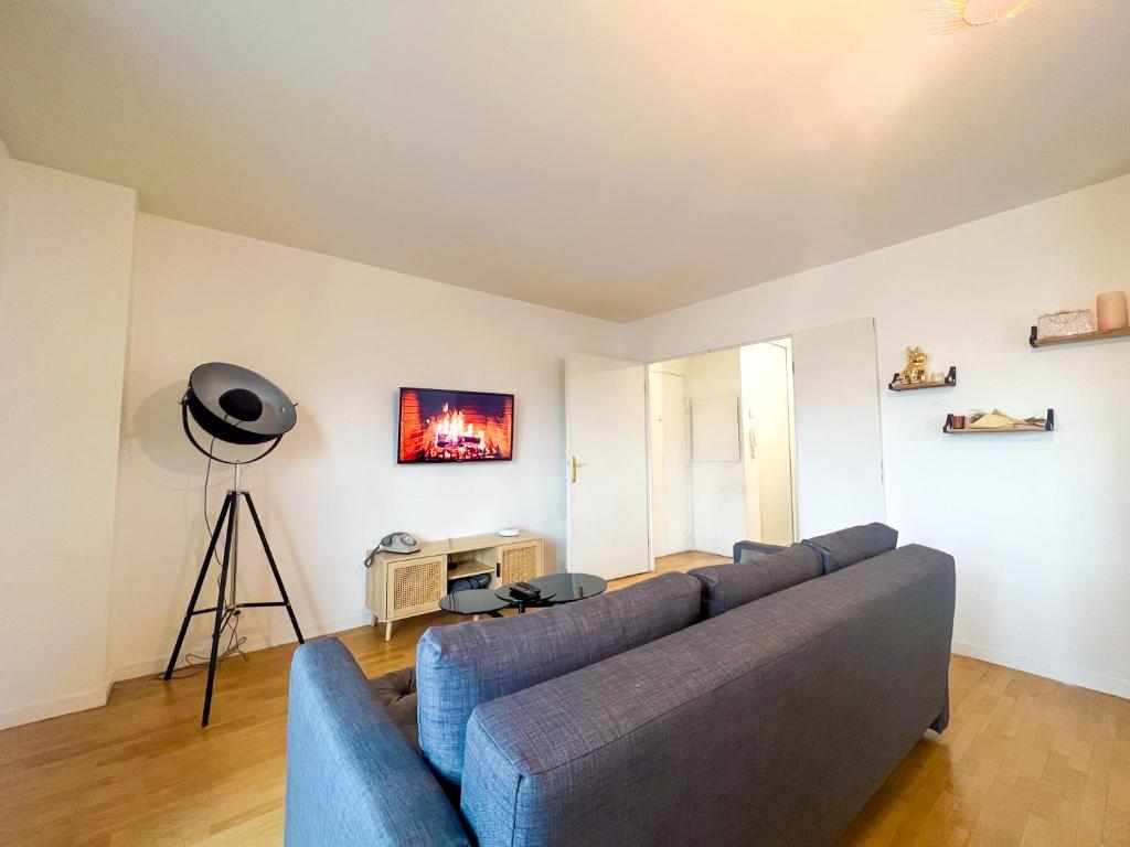 a living room with a blue couch in a room at Cosy & Spacieux, Paris 10 min + Parking privé. in Saint-Ouen