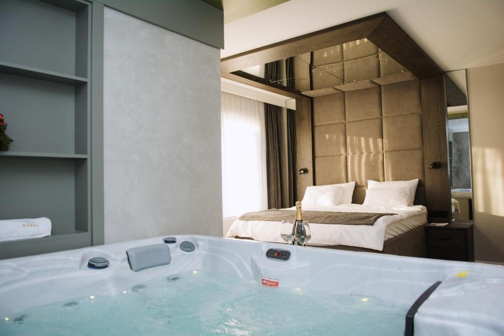 a bathroom with a bath tub with a bed in the background at Nobel apartmani Brčko in Brčko