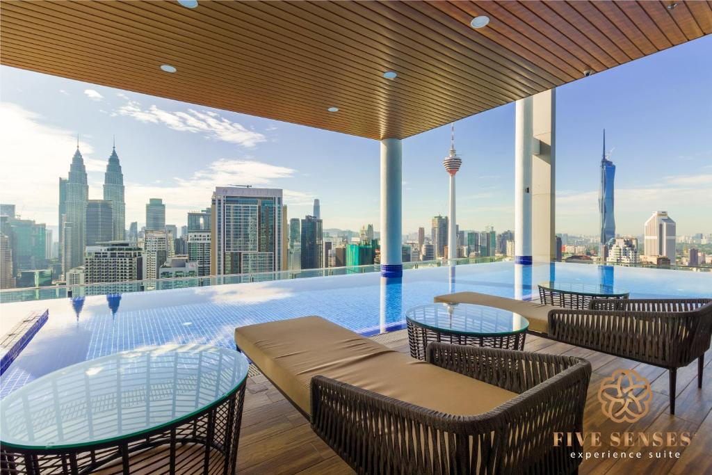 Una piscina con mesas y sillas y un horizonte de la ciudad. en The Colony &amp; The Luxe Signature Suites, KLCC, en Kuala Lumpur