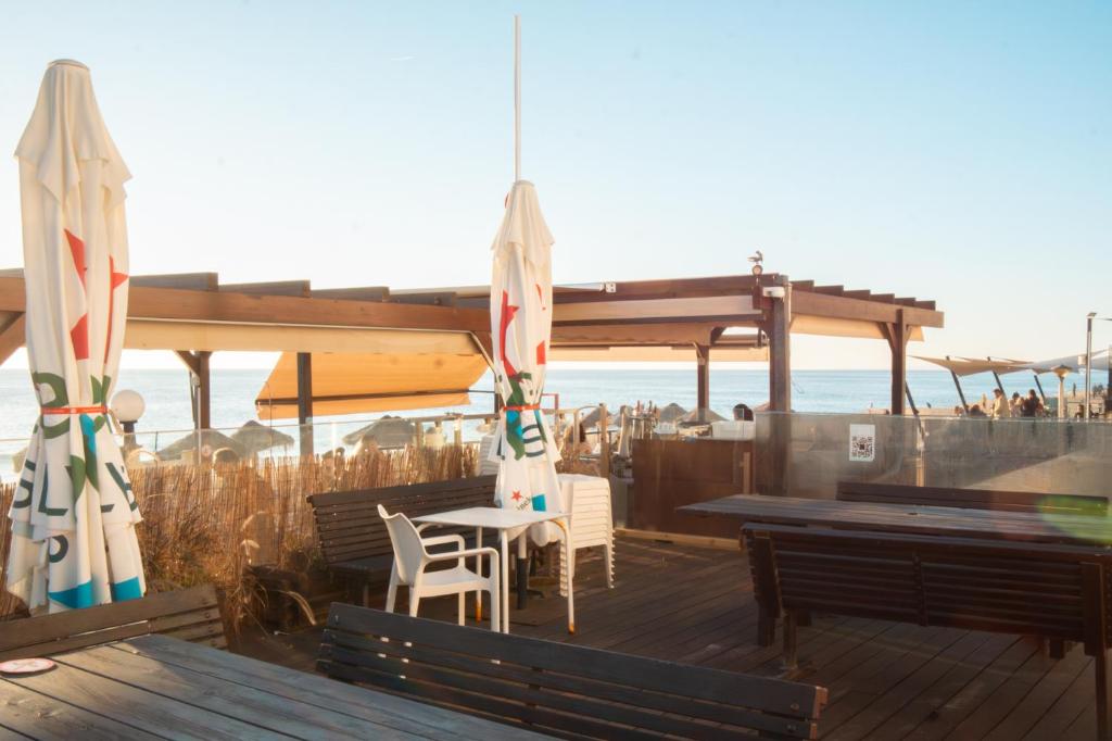 una terrazza con tavoli, sedie e ombrelloni di By the sea a Faro