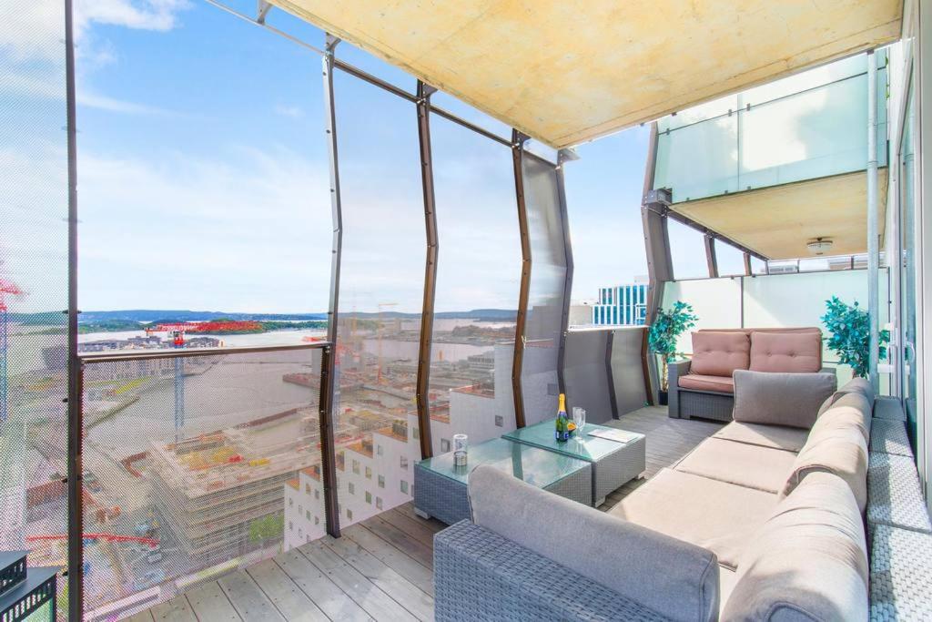 Super Central Designer Penthouse at 19th floor with Amazing View! في أوسلو: شرفة مع أريكة وطاولة