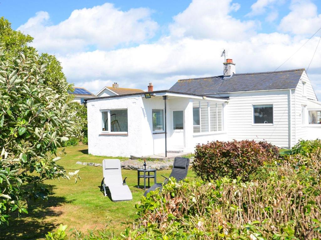 a white house with a yard with chairs and a table at Brookfield in Rhosneigr