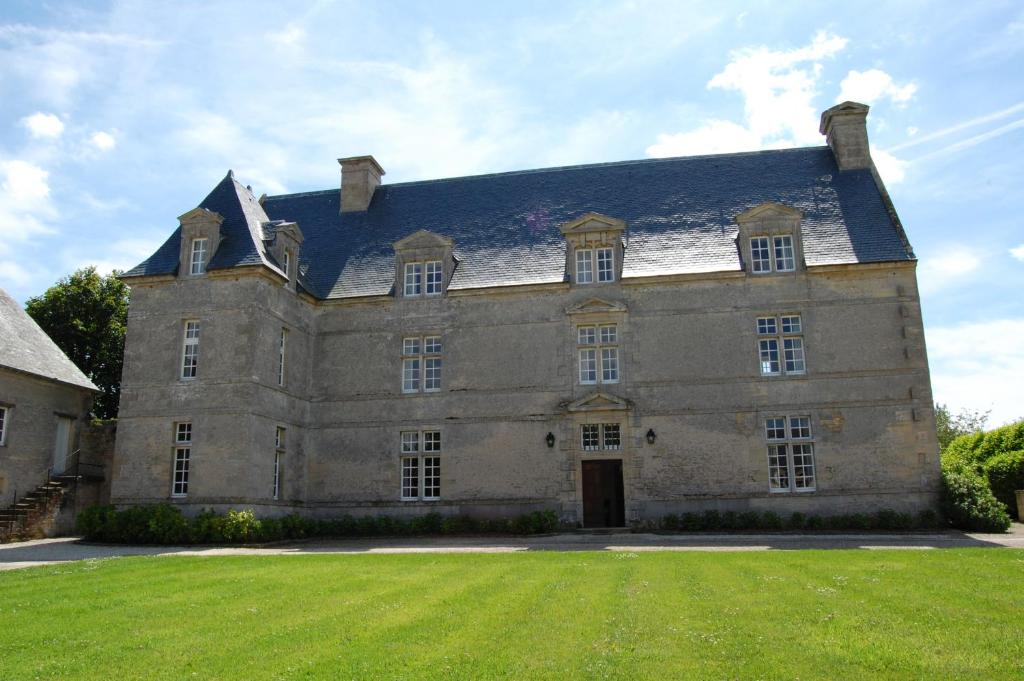 um grande edifício de pedra com um grande jardim de relva em La Grande Ferme Maison de Maître em Crépon