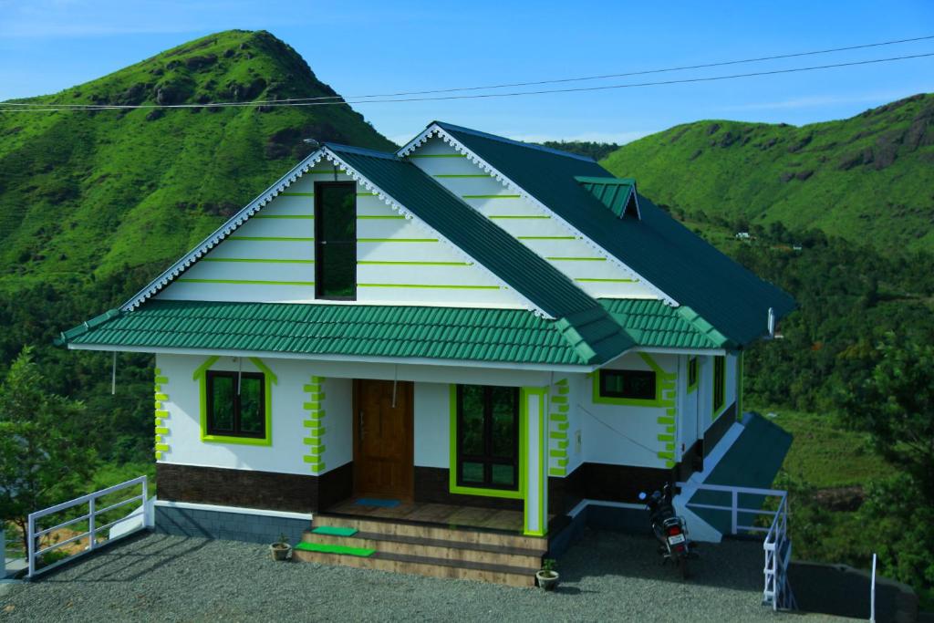 a small house with a green hill in the background at The Kissing Mountains in Vagamon