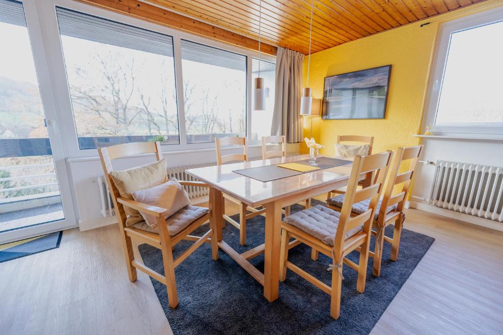 a dining room with a wooden table and chairs at Ferienhaus Schöne Aussicht Ferienwohnung Gelb in Hemfurth-Edersee
