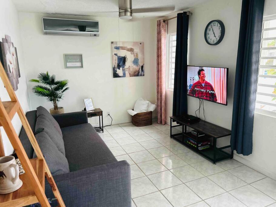 sala de estar con sofá y reloj en la pared en Studio21-B Centric Comfort House en Bayamon