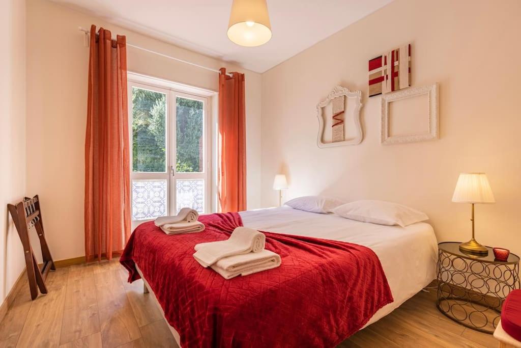 een slaapkamer met een bed met rode lakens en een raam bij Apartamento Jalles in Alenquer