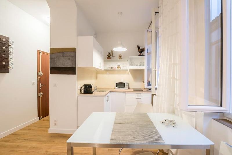 eine kleine weiße Küche mit einem Tisch darin in der Unterkunft Saint-Aubin - Centre-ville - Calme - Confortable in Toulouse