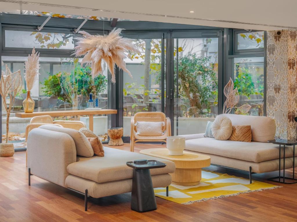 un salon avec deux canapés et des chaises et des fenêtres dans l'établissement Mercure Paris Gare Montparnasse TGV, à Paris