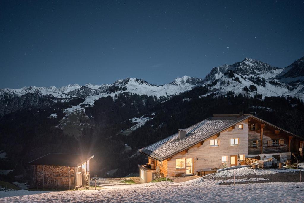 uma cabana de madeira na neve à noite com montanhas em Chalet Frederik em Fontanella