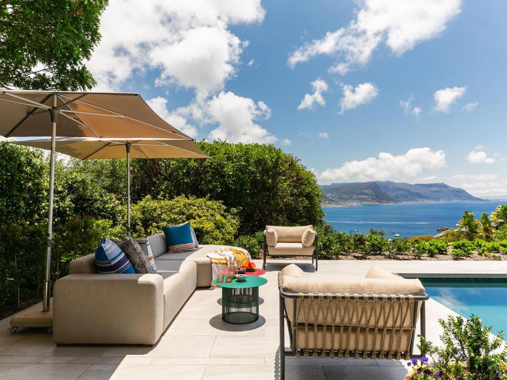 a patio with a couch and an umbrella and a pool at Villa Coste Simons Town in Simonʼs Town