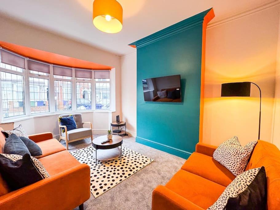 a living room with an orange couch and a blue wall at Vibrant Tranquility: What a gem! in Cleethorpes