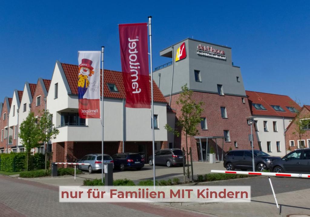 een gebouw met twee vlaggen ervoor bij Hotel Deichkrone - Familotel Nordsee in Norddeich
