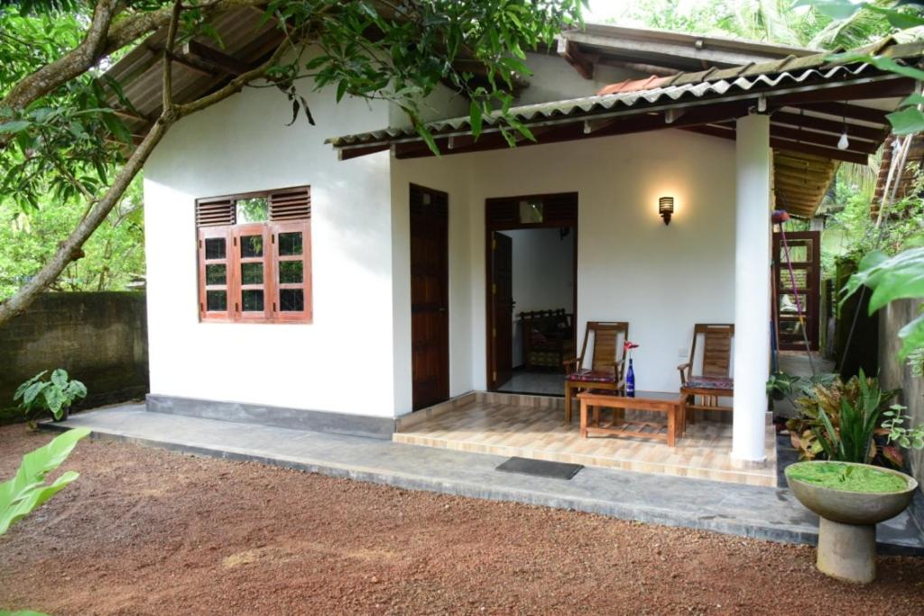 a small white house with a porch at Sanjee Villa Hikkaduwa in Hikkaduwa