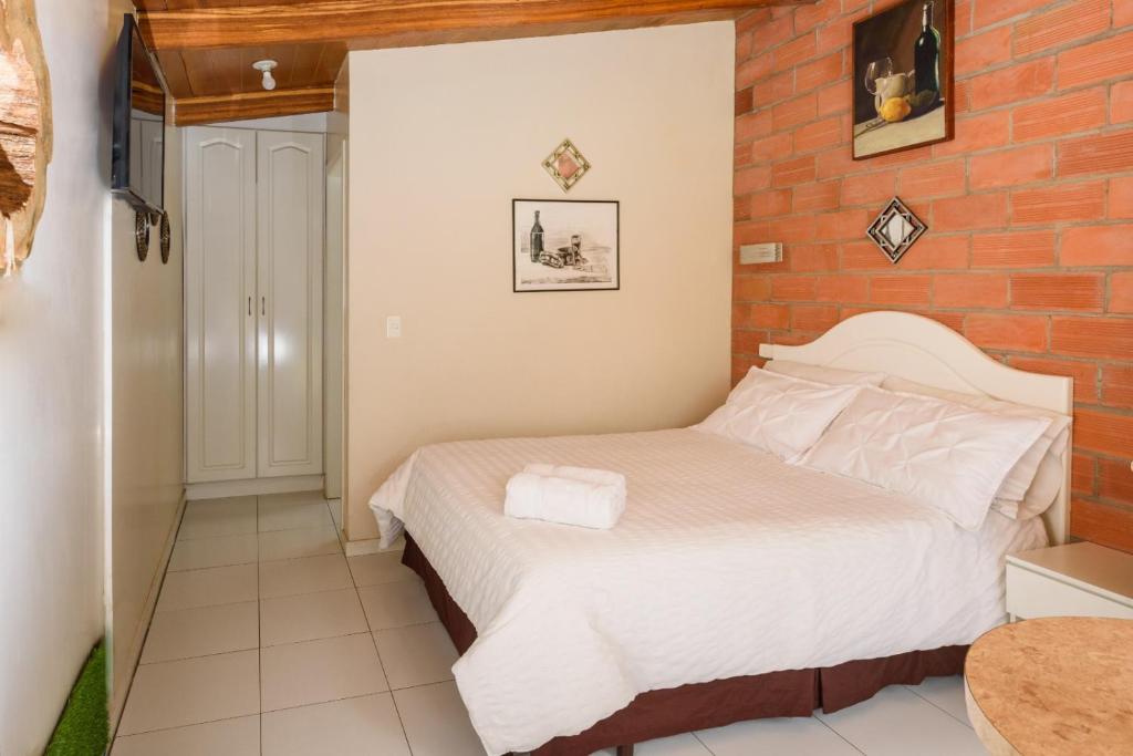 1 dormitorio con cama y pared de ladrillo en Casa Elalu, en Quito