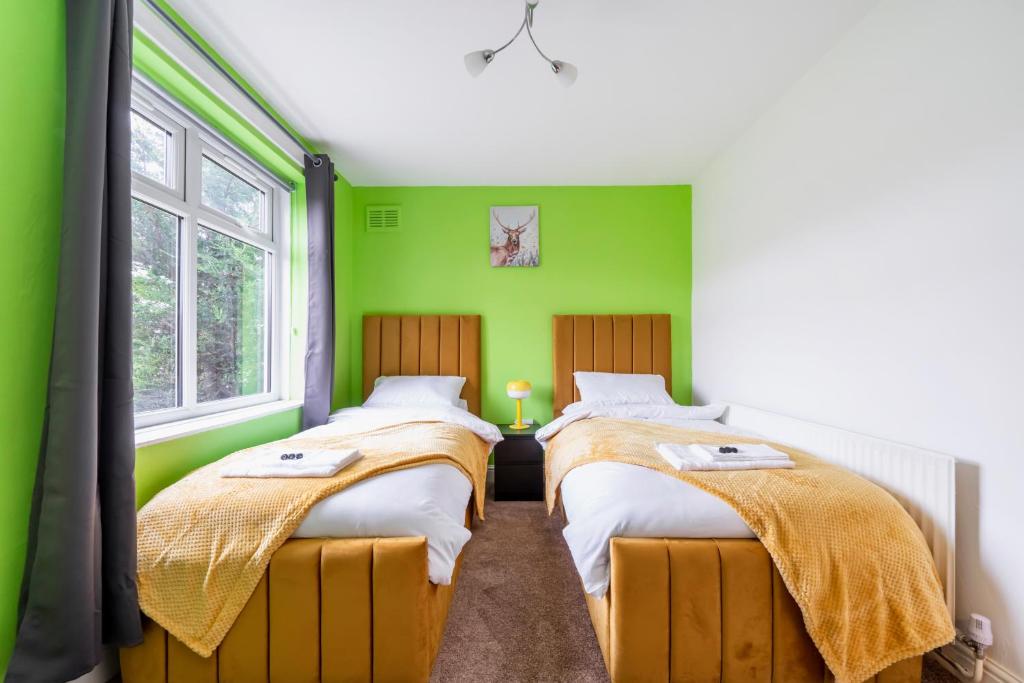 2 Betten in einem Zimmer mit grünen Wänden und Fenstern in der Unterkunft UKSAS Two bed house Free Parking in Redbridge