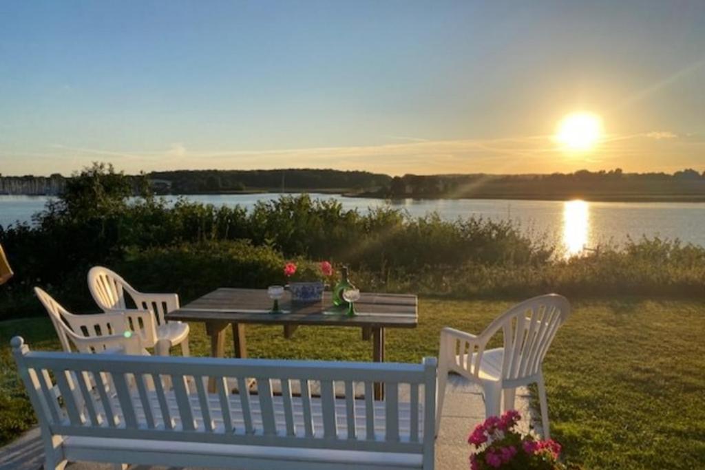 a picnic table with three chairs and a table with the sunset at Möwe in Kappeln