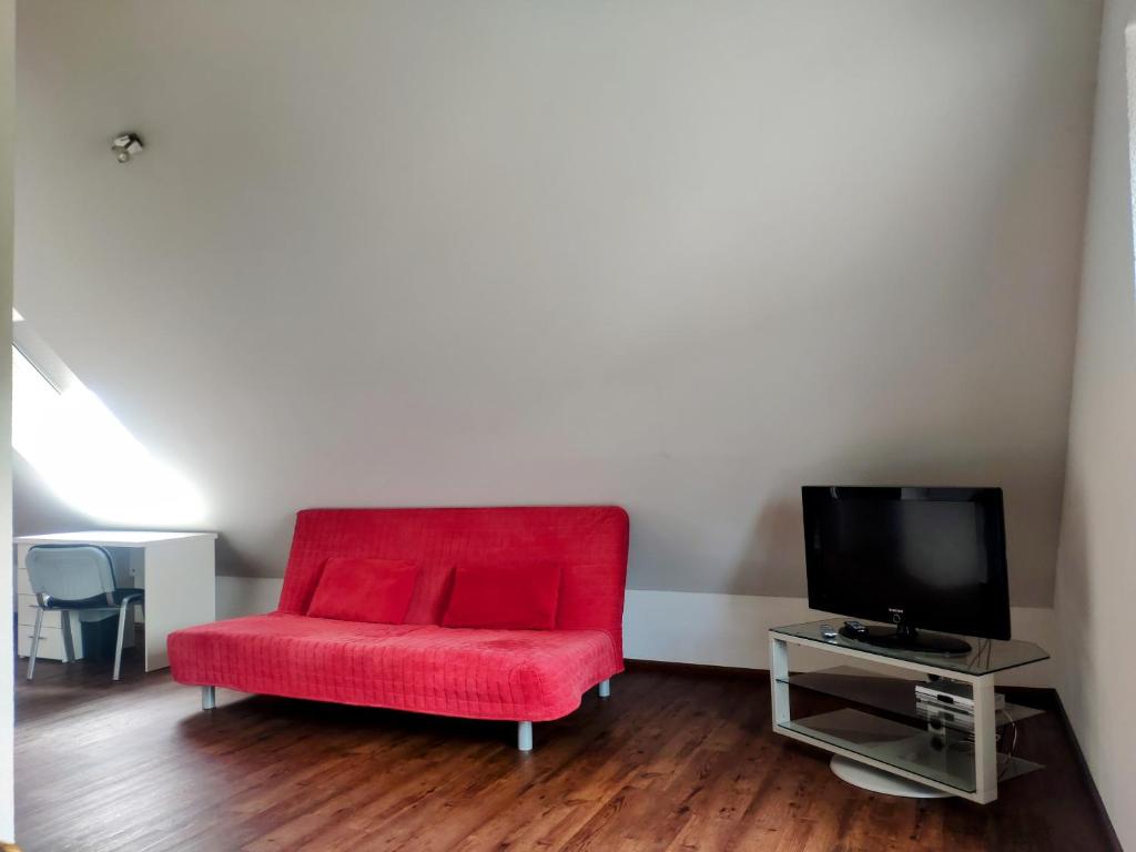 - Silla roja en la sala de estar con TV en das Apartmenthaus in Freiburg, en Freiburg im Breisgau
