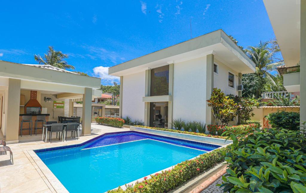 uma villa com piscina em frente a uma casa em Residencial João e Maria - Aptos 03 quartos em Porto Seguro