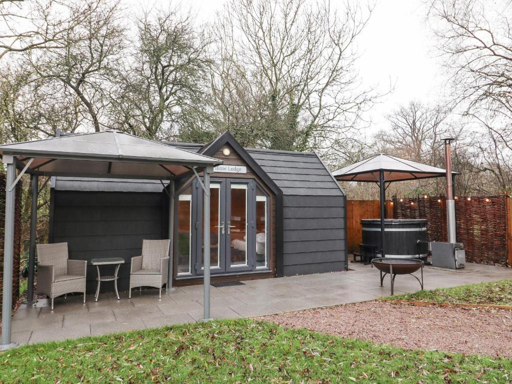 a black shed with a grill and an umbrella at Willow Lodge At Bridge Lake Farm & Fishery in Banbury