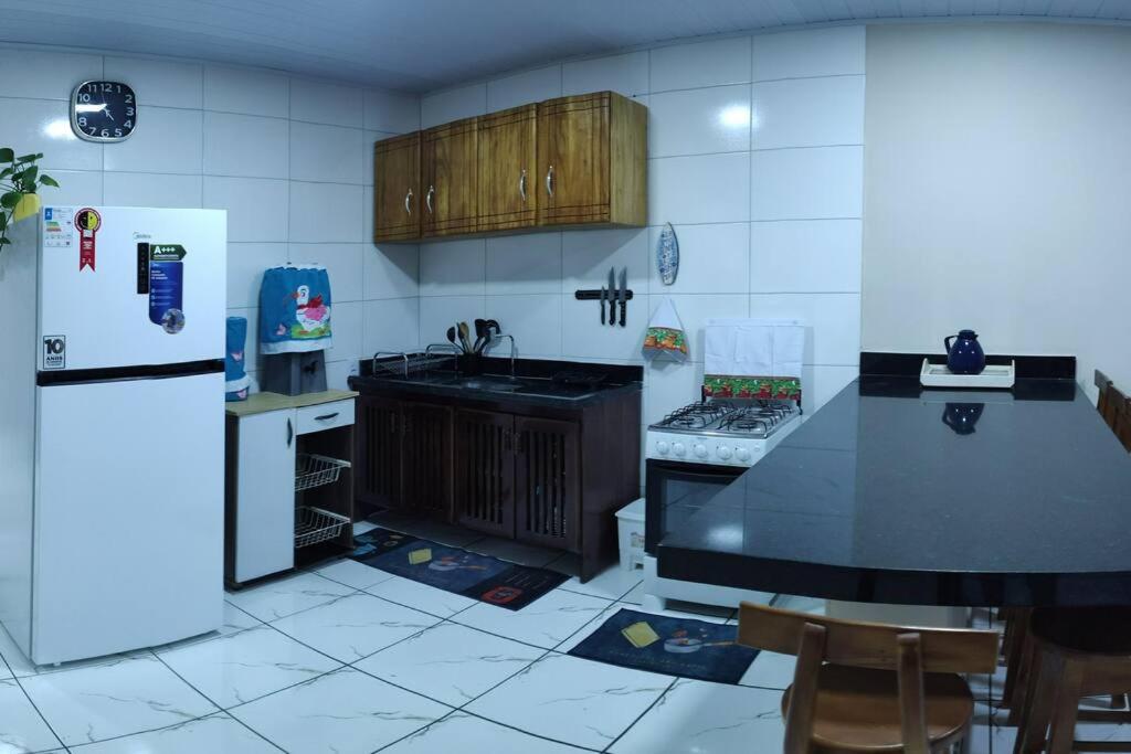 Il comprend une cuisine équipée d'un comptoir noir et d'un réfrigérateur. dans l'établissement Casa para temporada, à Porto Seguro
