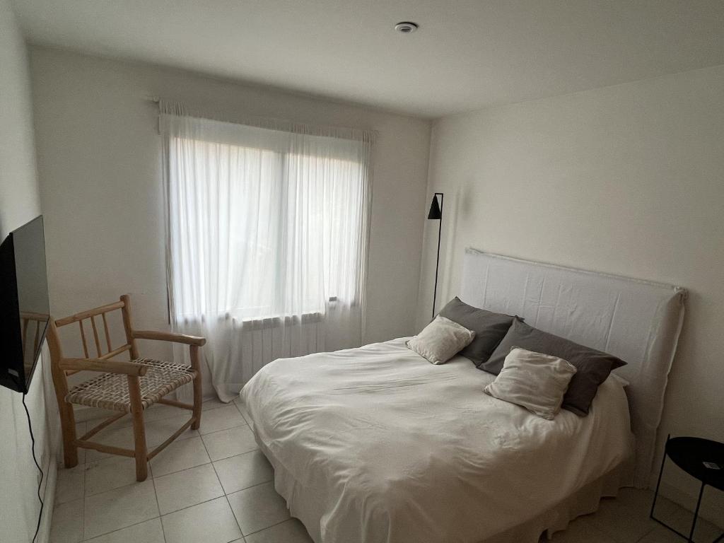 Un dormitorio con una cama, una silla y una ventana en Villegas Céntrico - Andarlibre, en San Martín de los Andes