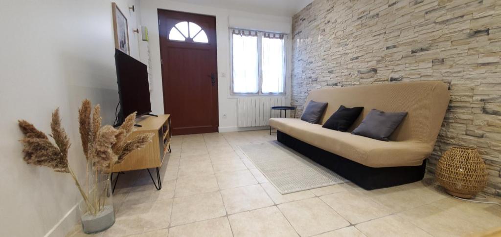a living room with a couch and a brick wall at Orly Serenity House Paris 20min Aéroport 12min Parking gratuit in Orly
