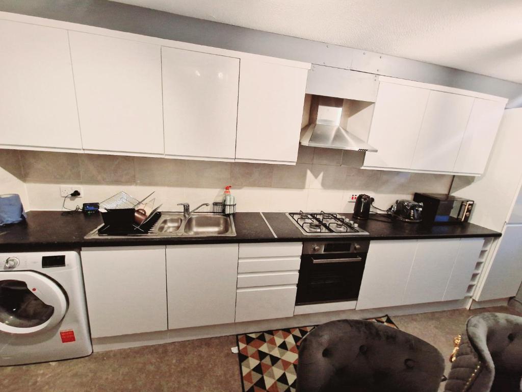 a kitchen with white cabinets and a sink at Flat 16 Homedale house in Sutton