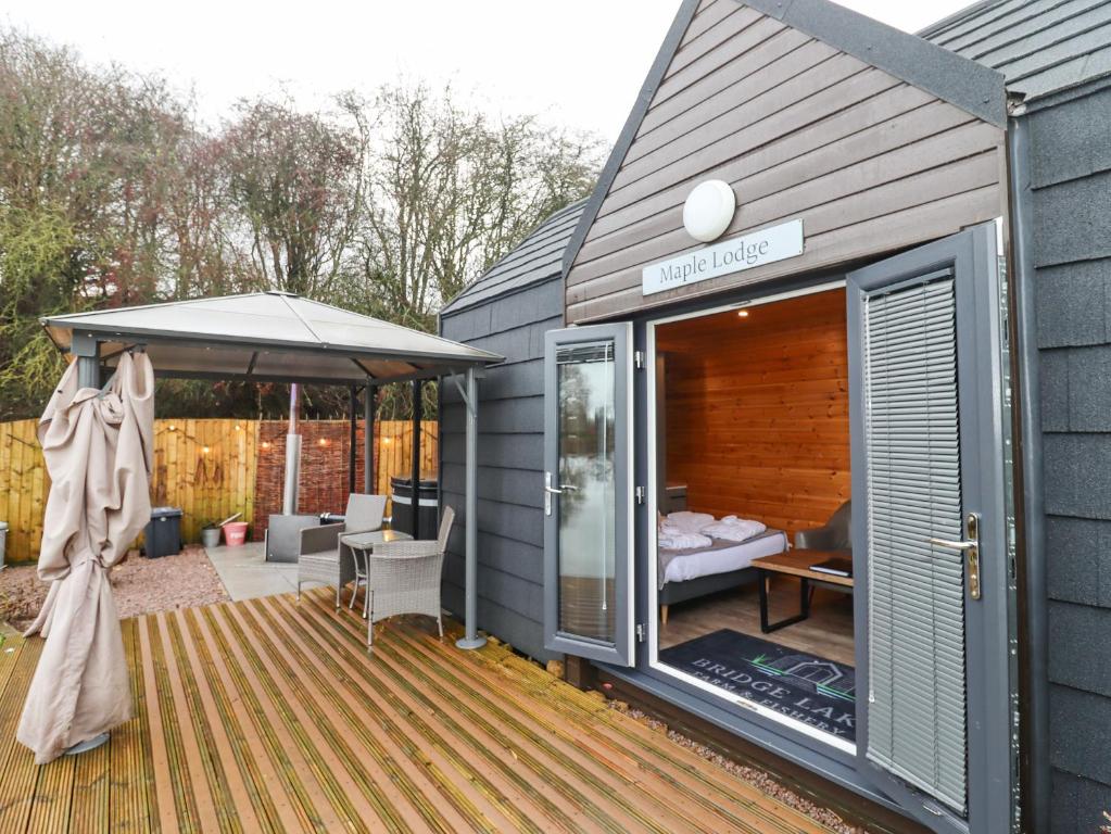 a tiny house with a deck with a patio at Maple Lodge at Bridge Lake Farm & Fishery in Banbury