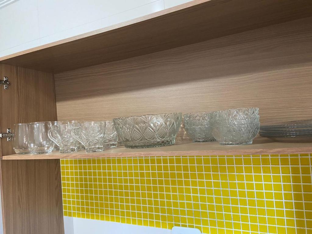 a shelf with glass bowls and plates on it at Maria Rosa Aparts in Matinhos