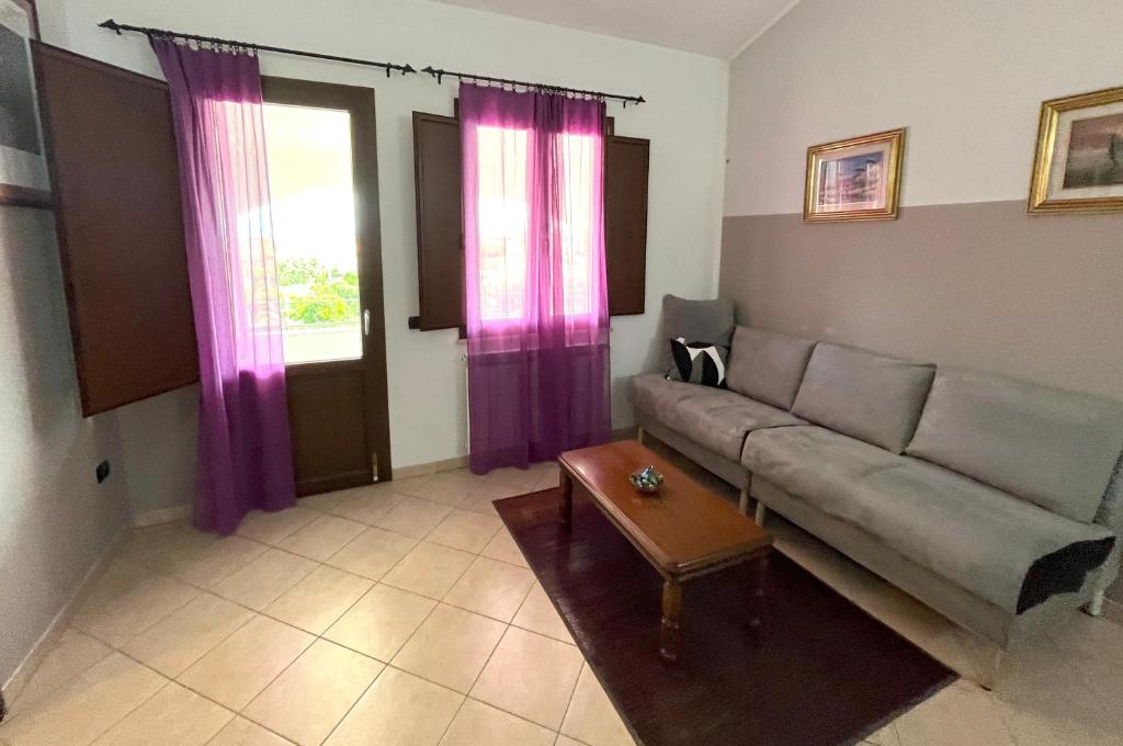 een woonkamer met een bank en paarse gordijnen bij Casa Mimì in Càbras