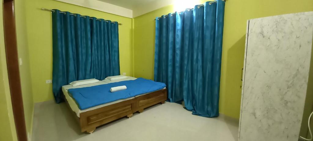 um pequeno quarto com uma cama e cortinas azuis em Kaziranga Balaji homestay em Kaziranga