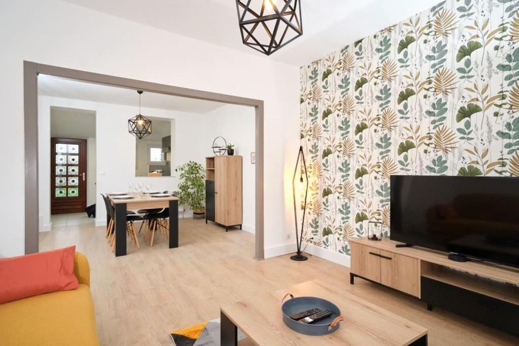 a living room with a television and a dining room at Maison 2 chambres, jardin in Rethel