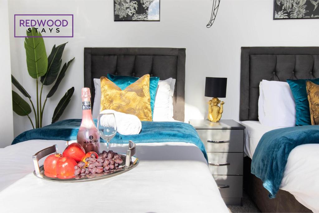 bandeja de fruta y botella de vino en la cama en Modern 1 Bed 1 Bath Apartment for Corporates & Contractors, FREE Parking, Wi-Fi & Netflix By REDWOOD STAYS, en Farnborough