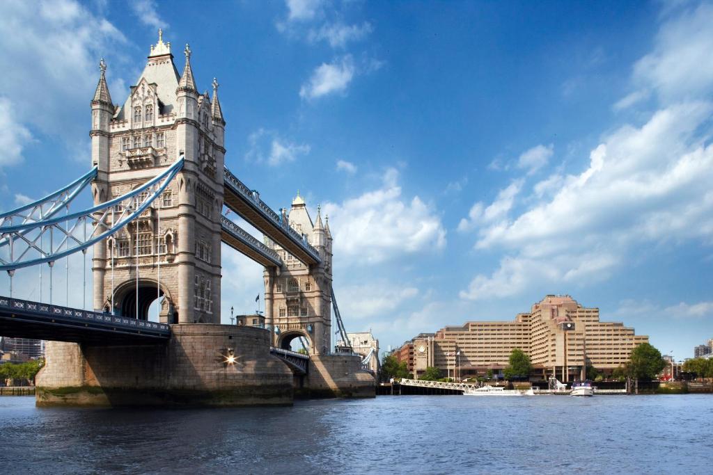 The Tower Hotel, London في لندن: جسر فوق الماء مع مباني في الخلف