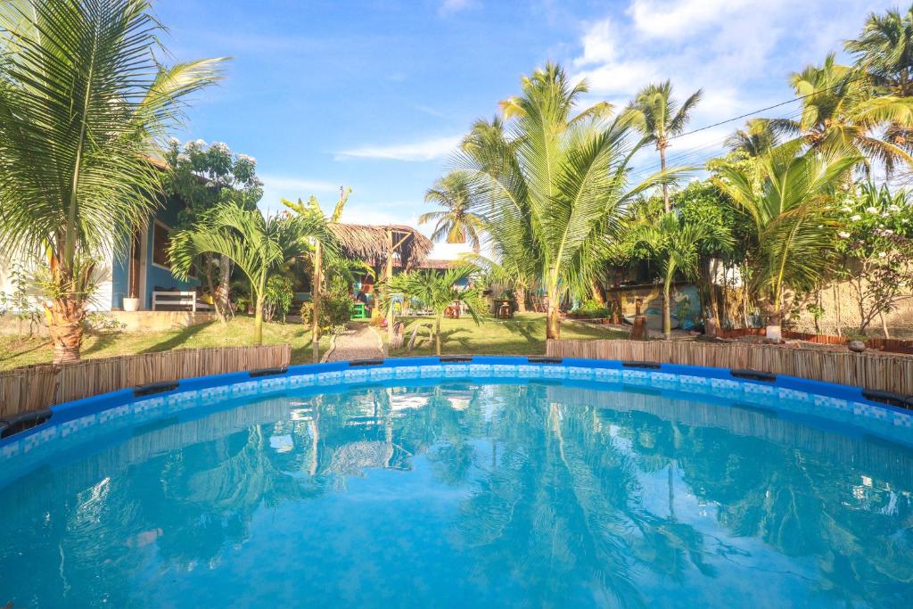 a large swimming pool in a yard with palm trees at Back to the Beach Hostel - Pipa in Pipa