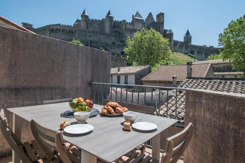 a table with a plate of food on a balcony at Le Saint Gimer - Vue sur la Cité Médiévale - Climatisation in Carcassonne