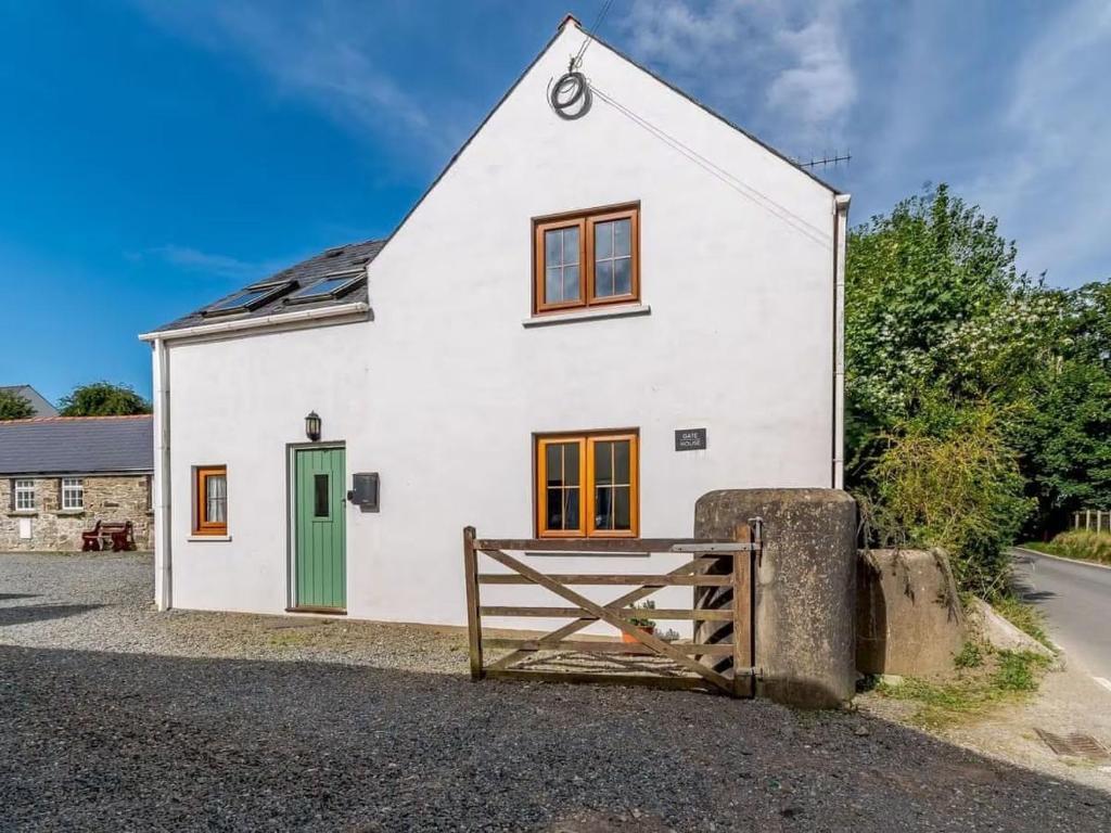 a white house with a green door and a gate at The Gatehouse at Y Gwesty Bach in Jordanston